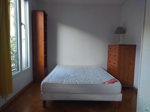 une chambre avec un lit, une commode et une fenêtre dans l'établissement Chambre de charme sur jardin, à Courbevoie