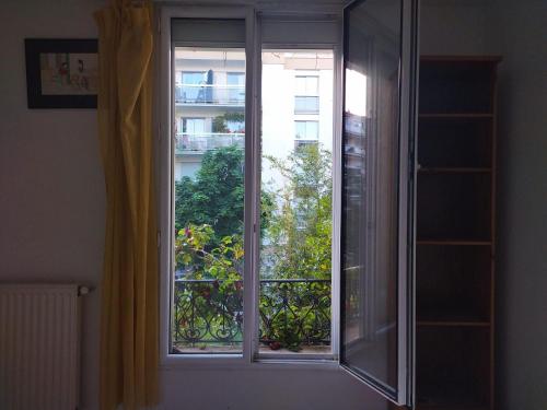 une fenêtre avec vue sur un balcon dans l'établissement Chambre de charme sur jardin, à Courbevoie
