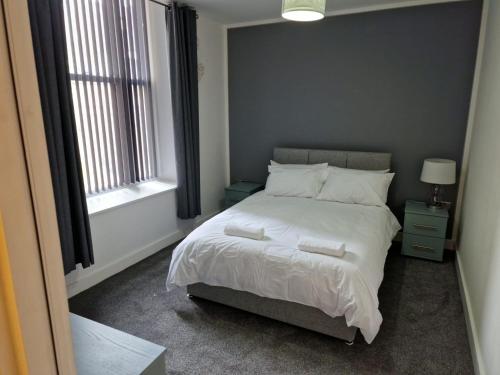 - une chambre avec un lit doté de draps et d'oreillers blancs dans l'établissement Suffolk House Apartments HU1, à Hull