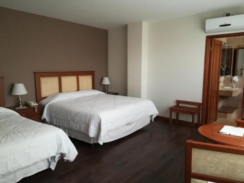 a hotel room with two beds and a table at Gran Hotel Toloma in Cochabamba