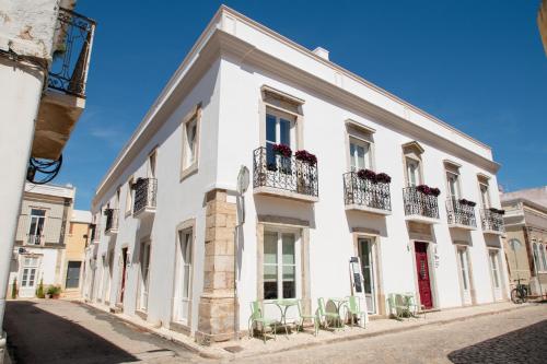 a white building with chairs on a street at Casa Amor Olhão in Olhão