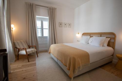 a bedroom with a bed and a chair and a window at Casa Amor Olhão in Olhão