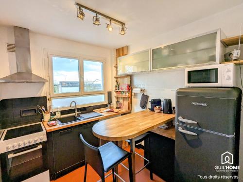 une cuisine avec une table en bois et un réfrigérateur dans l'établissement Le Balcon de l'Europe - Cosy - Parking - Tramway, à Orléans