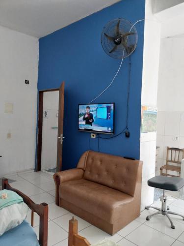 ein Wohnzimmer mit einem Sofa und einem TV an einer blauen Wand in der Unterkunft POUSADA PERLLA's Pindamonhangaba in Pindamonhangaba