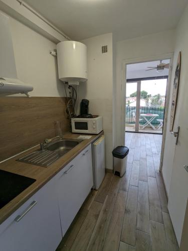 une cuisine avec un évier et un micro-ondes dans l'établissement Studio climatisé avec balcon - Vue montagne - 50 m de la plage, à Canet