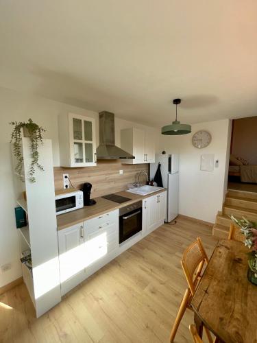 une cuisine avec des armoires blanches et une table en bois dans l'établissement Bel appartement à Céret, à Céret