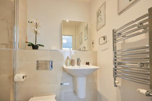 a white bathroom with a sink and a shower at Canary Haven- Luxury 2 bedroom 2 bathroom Apartment in London