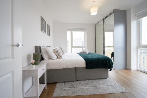 a white bedroom with a bed and a mirror at Canary Haven- Luxury 2 bedroom 2 bathroom Apartment in London