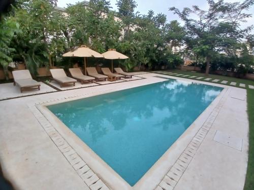 a swimming pool with chairs and umbrellas at Sandbox Apartment 4 Diani Beach Kenya in Ukunda