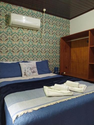 a bedroom with a blue bed with towels on it at Pousada do Pescador in Florianópolis