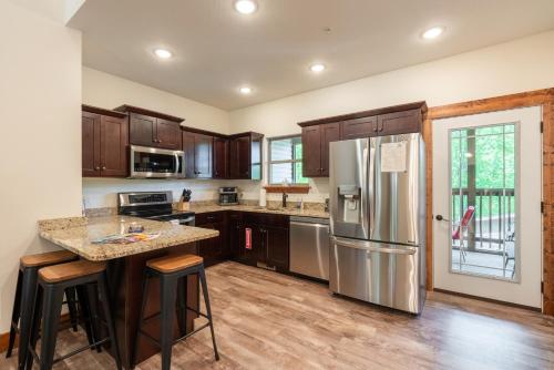 eine Küche mit Holzschränken und einem Kühlschrank aus Edelstahl in der Unterkunft 3BR Walk-In Near Silver Dollar City - Game Room - Pool - FREE TICKETS INCLUDED - RR93A in Branson