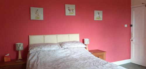 a bedroom with a bed with a red wall at Plumtree House in Brigsteer