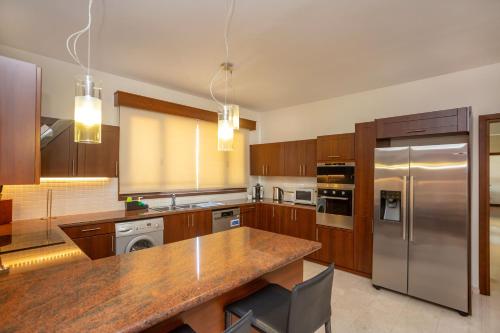 a kitchen with wooden cabinets and stainless steel appliances at Hallmark Beach by TrulyCyprus in Limassol