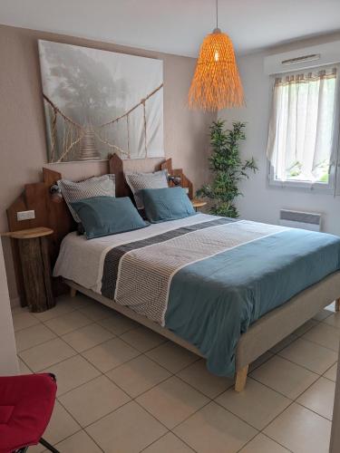 une chambre avec un grand lit avec des oreillers bleus dans l'établissement Charmant appartement de 41m2 avec linges de maison et ménage compris, 2 pièces à Lamalou-les-Bains pour 2 personnes, à Lamalou-les-Bains