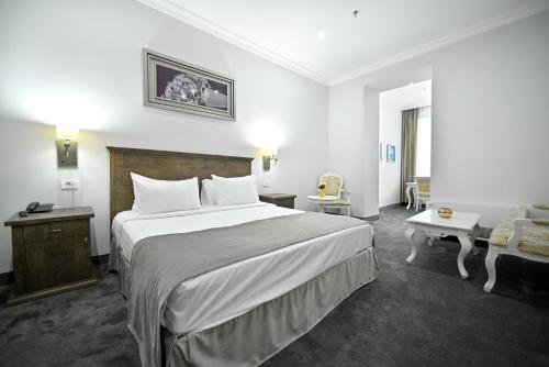 a hotel room with a large bed and a couch at Address Hotel Yerevan by Imperial in Yerevan