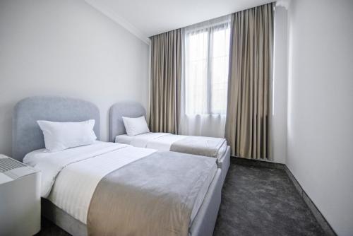 two beds in a hotel room with a window at Address Hotel Yerevan by Imperial in Yerevan