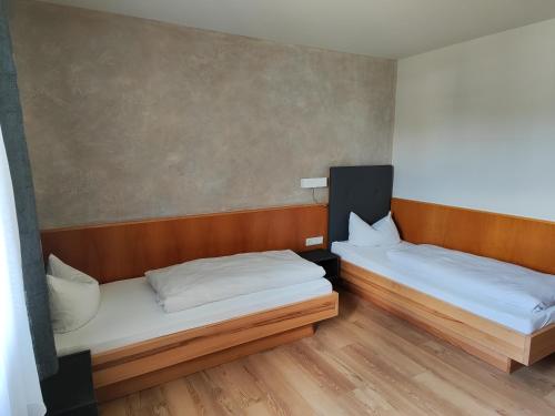 two beds in a room with wooden floors at Gasthof Zahler in Röfingen