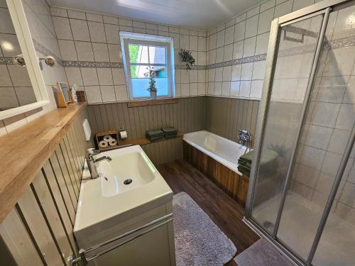 a bathroom with a sink and a shower and a tub at Ferienhaus Fehntraum - Entdecke Ostfriesland in Großefehn 