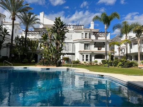een groot wit huis met een zwembad ervoor bij Beautiful 2 bedroom Apartment in Puerto Banus ! in Marbella
