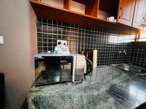 a kitchen with a counter top with a microwave at The Urban Edge in Makerere