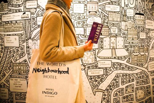 a woman holding a book in front of a wall at Hotel Indigo York by IHG in York