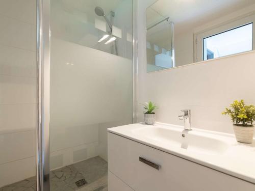 une salle de bain blanche avec un lavabo et un miroir dans l'établissement Appartement calme près du centre et pistes, balcon sud, navette gratuite - FR-1-296-168, à Saint-Lary-Soulan