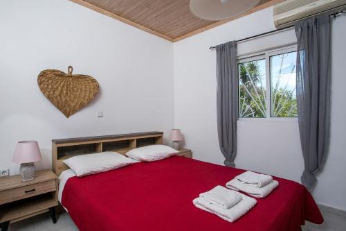 a bedroom with a red bed with two towels on it at Tinas Dreams By The Sea in Afantou