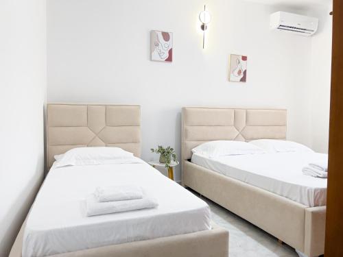 two beds in a bedroom with white walls at Boulevard Apartaments - Vlora in Vlorë