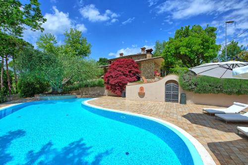 a swimming pool with an umbrella and a house at Villa Paradiso by PosarelliVillas in Nestore