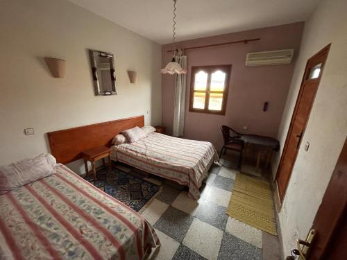 1 dormitorio con 2 camas, escritorio y silla en Hotel Tanout en Azilal