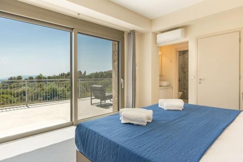 a bedroom with a blue bed and a large window at Brand New Kefalonia Stone Villas - Villa Trapezaki Tranquility in Trapezaki