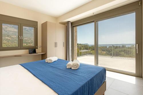 a bedroom with a blue bed with towels on it at Brand New Kefalonia Stone Villas - Villa Trapezaki Tranquility in Trapezaki