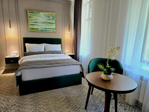 Maestro Address Hotel في باكو: غرفة في الفندق مع سرير وطاولة مع منضدة sidx