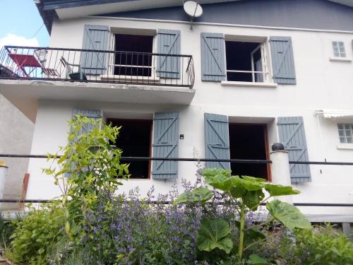 a white house with a balcony and purple flowers at le lys dans la vallée d ustou in Ustou