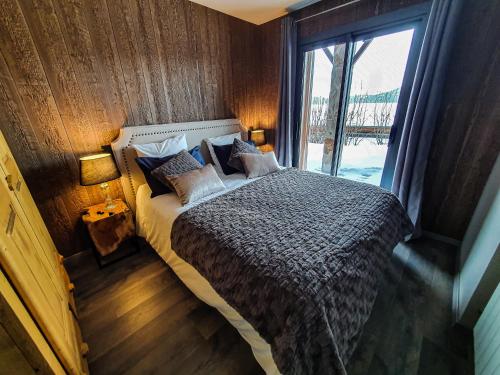 une chambre avec un lit avec une grande fenêtre dans l'établissement Les Fermes de Cal Panche : Le Bas de Chalet, aux Angles