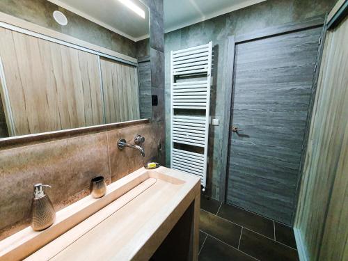 une salle de bain avec un lavabo et un grand miroir dans l'établissement Les Fermes de Cal Panche : Le Bas de Chalet, aux Angles