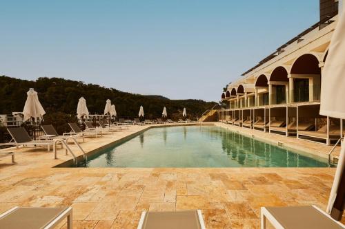 duży basen z leżakami i parasolami w obiekcie Cala San Miguel Hotel Ibiza, Curio Collection by Hilton, Adults only w mieście Puerto de San Miguel