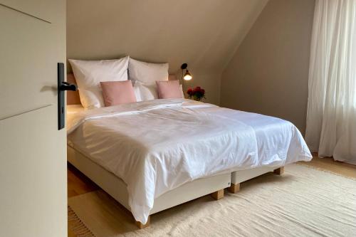 a bedroom with a large white bed with pink pillows at Das Winzereck - 4 Sterne Ferienhaus in der Südpfalz in Ranschbach