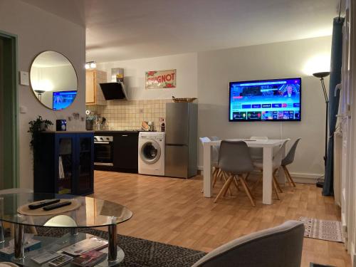 un soggiorno con tavolo e TV a parete di Chaleureuse maison quartier calme hôpital a Châteauroux