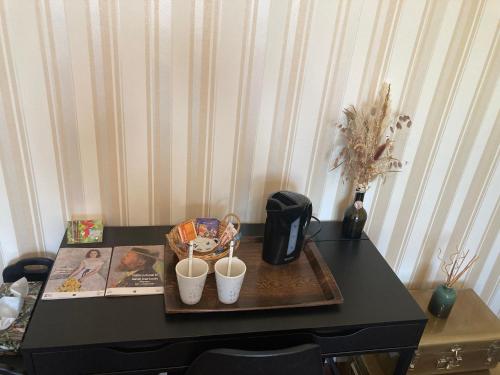 une table noire avec deux tasses en haut dans l'établissement Chambre au calme, à Lagarrigue