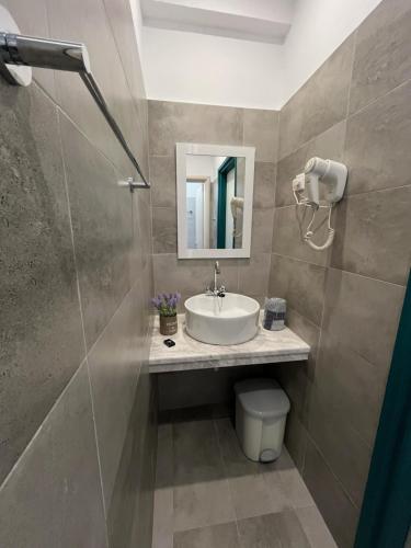 a bathroom with a sink and a toilet and a mirror at Angeliki Beach Hotel in Megali Ammos