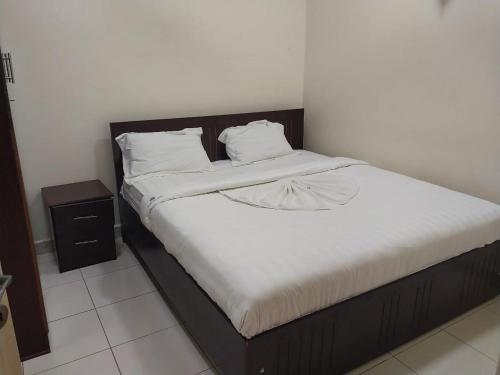 een bed met witte lakens en een houten hoofdeinde bij Tulba Hotel and Residences in Djoeba