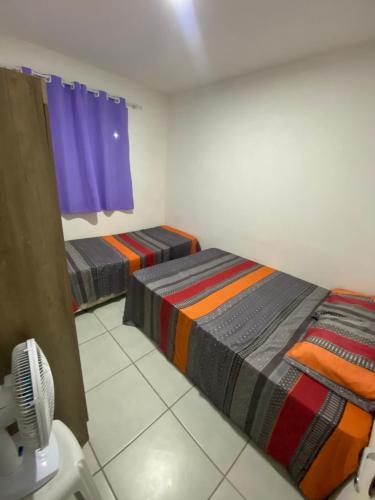 a room with two beds and a fan in it at Condomínio encantador in Caruaru
