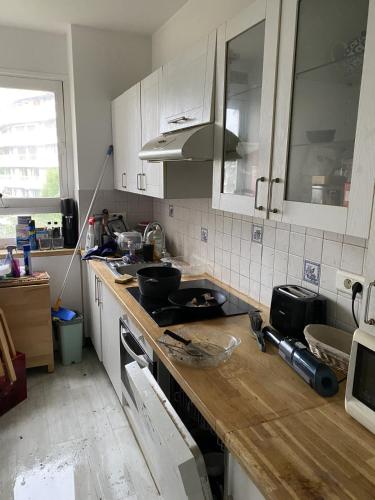 une cuisine avec des armoires blanches et un comptoir en bois dans l'établissement Room private, à Paris