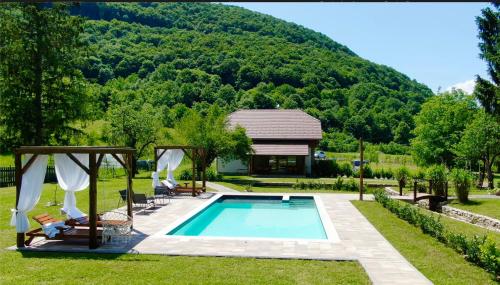 a swimming pool in a garden with a house at Vacation House Studenac in Bihać