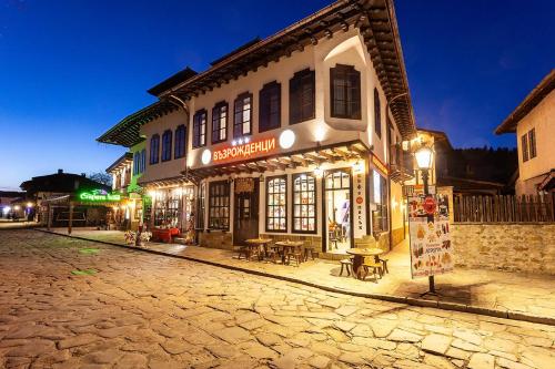 a building on a cobblestone street at night at Complex Vazrozhdentsi in Tryavna