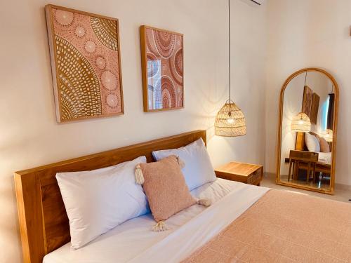 a bedroom with a bed with white sheets and a mirror at The Hideaway Canggu in Canggu
