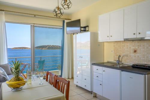 eine Küche und ein Esszimmer mit Meerblick in der Unterkunft Perla Apartments in Agios Nikolaos