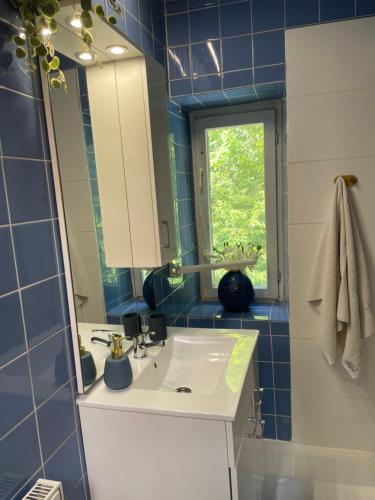 a blue tiled bathroom with a sink and a mirror at Willa Toskania in Lądek-Zdrój