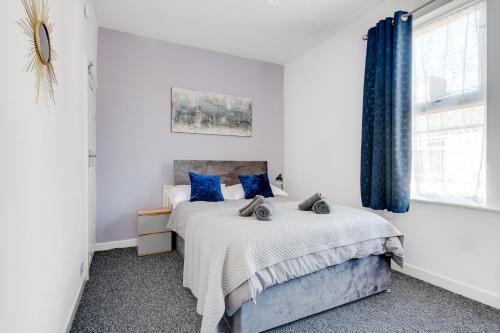 - une chambre blanche avec un lit et des oreillers bleus dans l'établissement Great Get Away, à Litherland